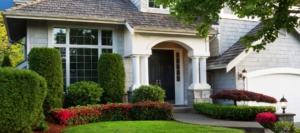 Front view of a suburban home in Alamo Heights, TX, featuring manicured bushes, flower beds, and a covered entryway with white columns